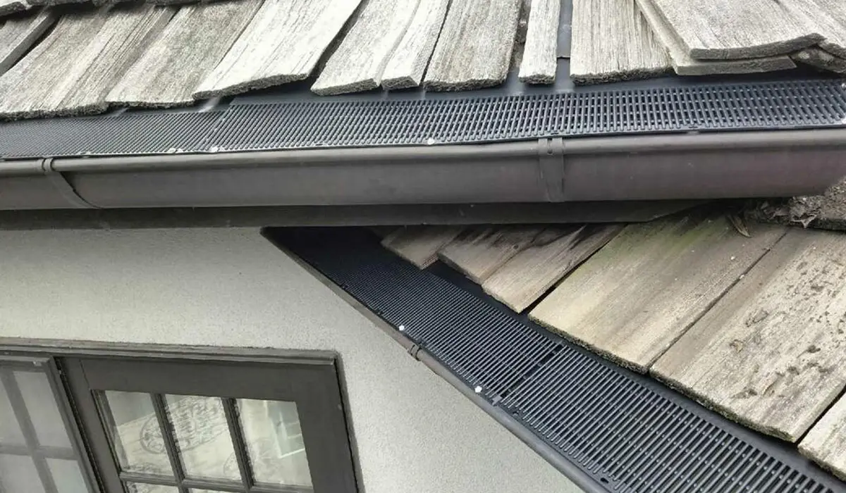 Metal Gutter Guards Metal gutter guards installed along worn wooden roofline, preventing debris buildup and supporting proper water drainage.