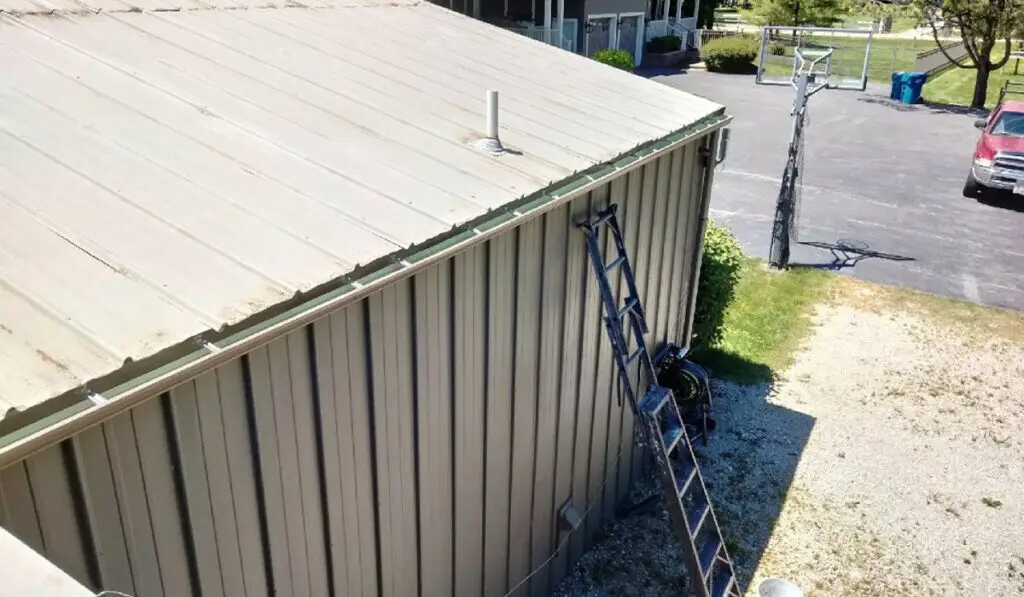 a house gutter and a ladder leaned against a wall | gutter cleaning