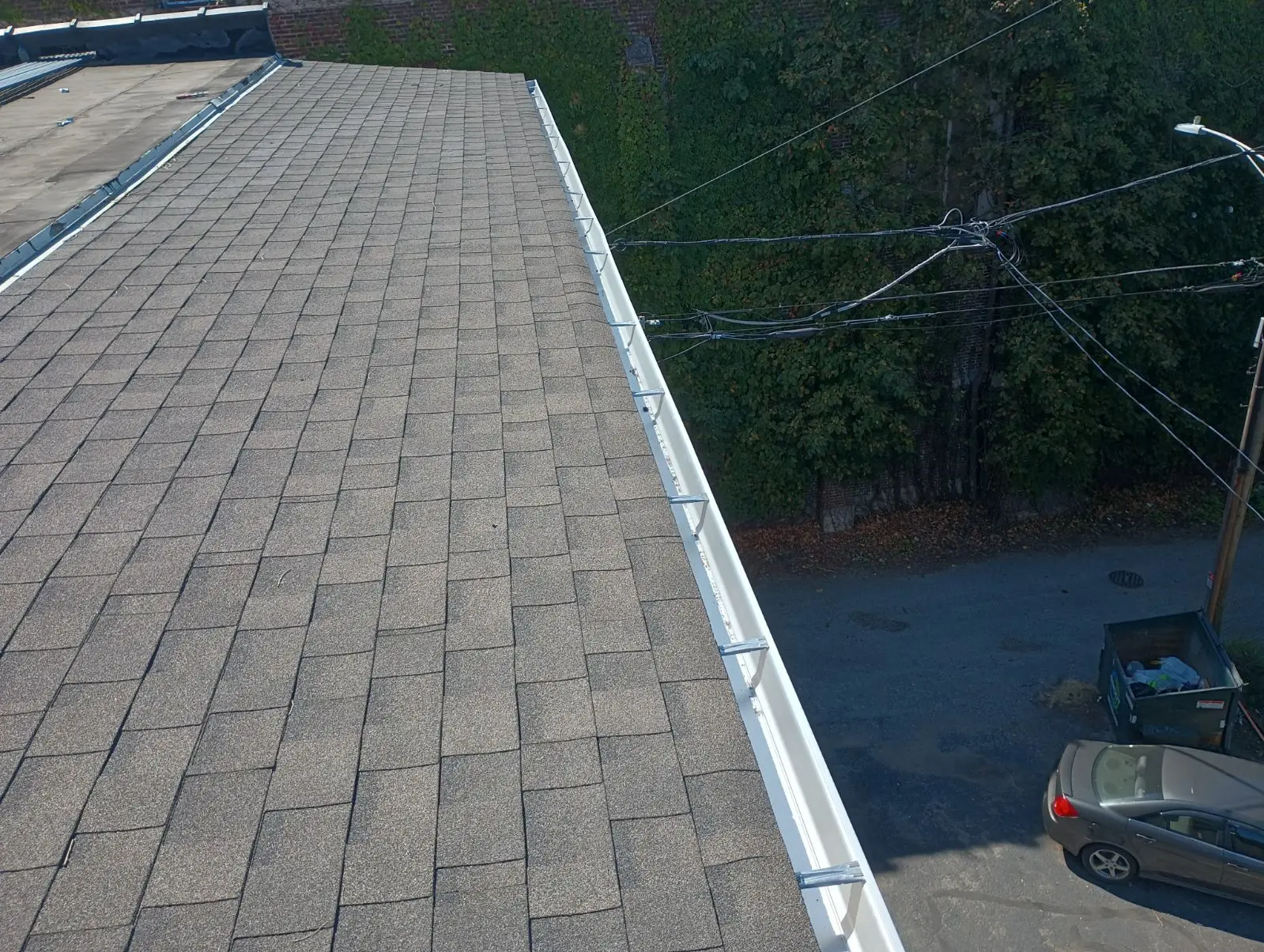 Seamless gutters installed on shingle roof showing clean slope and no visible joints