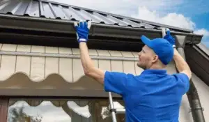 Technician performing gutter repair on a residential home’s drainage system.