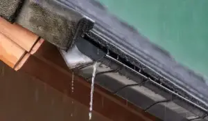 Rain overflowing from clogged gutter systems during intense summer storm on a residential Illinois home.